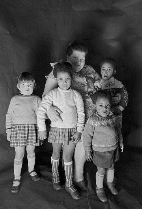 Daniel Meadows: Portrait of a foster mother with children in Meadows's free photographic studio on Greame Street, Moss Side, Manchester, February - April 1972